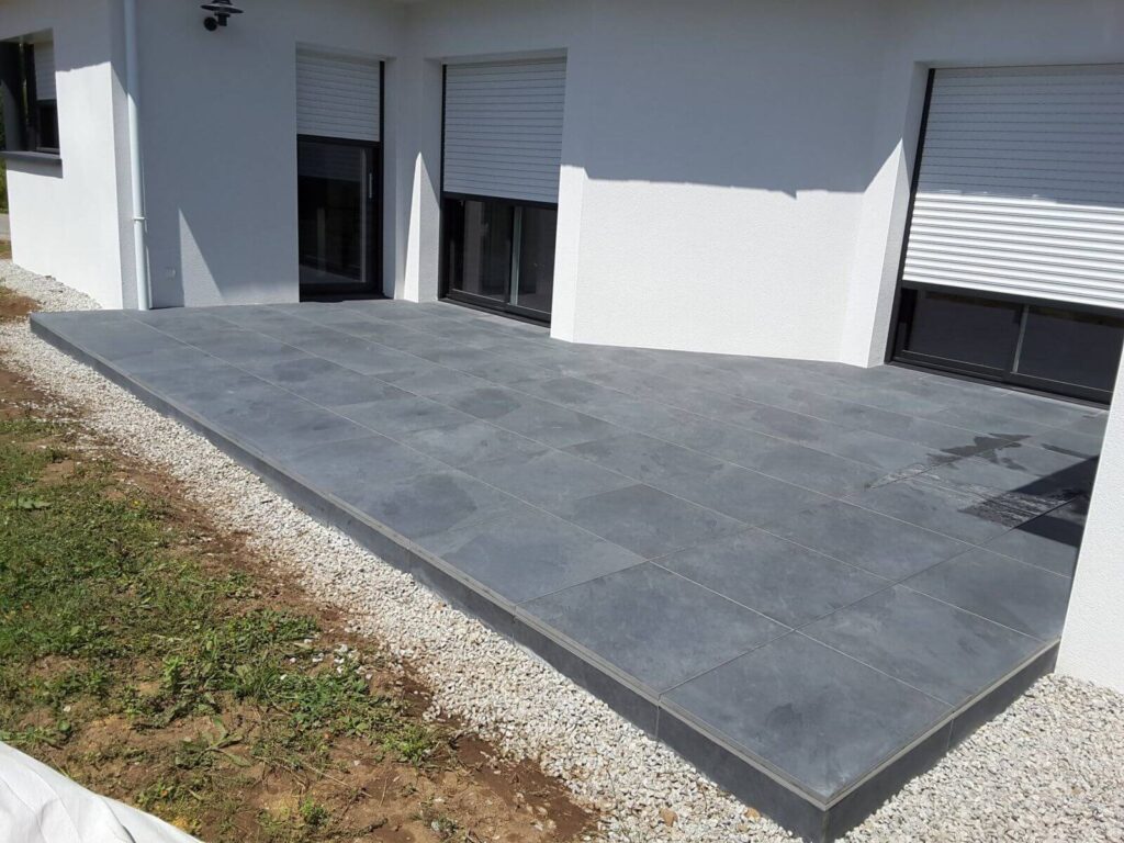 Large grey paving slabs laid beside a white house with a gravel edge