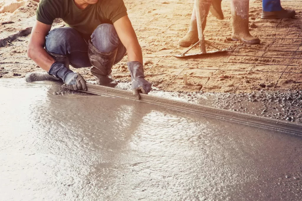 Worker levelling fresh concrete with a screed board